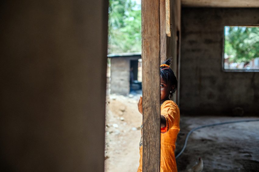 Girl from Senegal stands in a doorway.