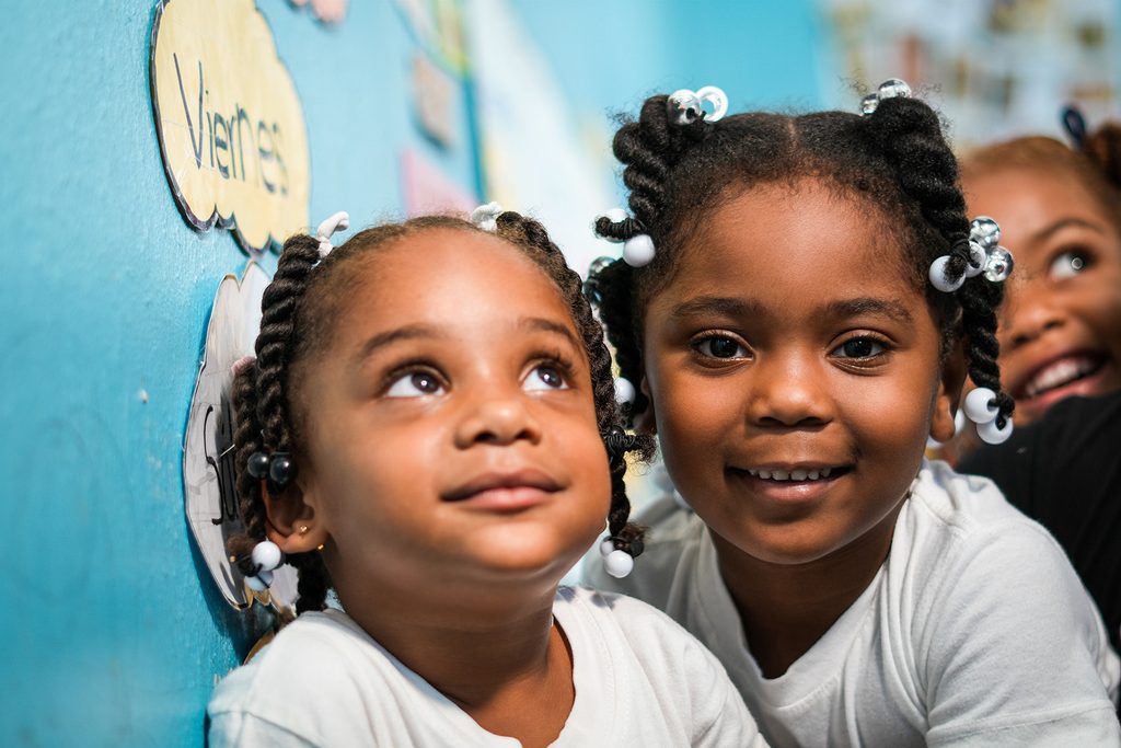 Two toddlers in a nursery smiling at the camera