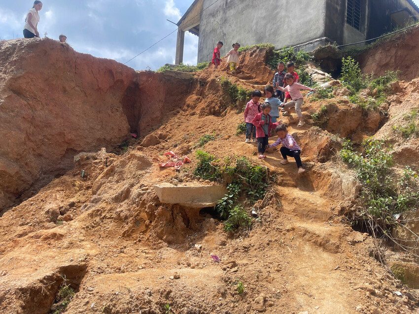 Children climb down a hillside path eroded by a landslide.