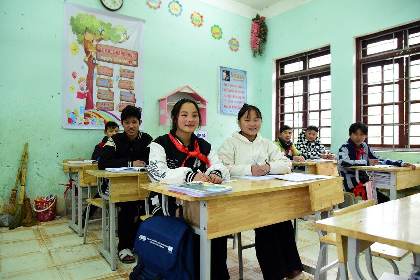 Students sit at desks in a classroom.