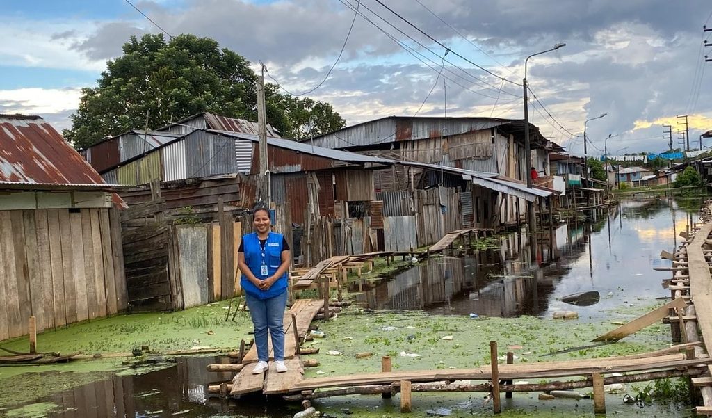 Claudia stands in front of houses in a flood prone community in Loreto region.