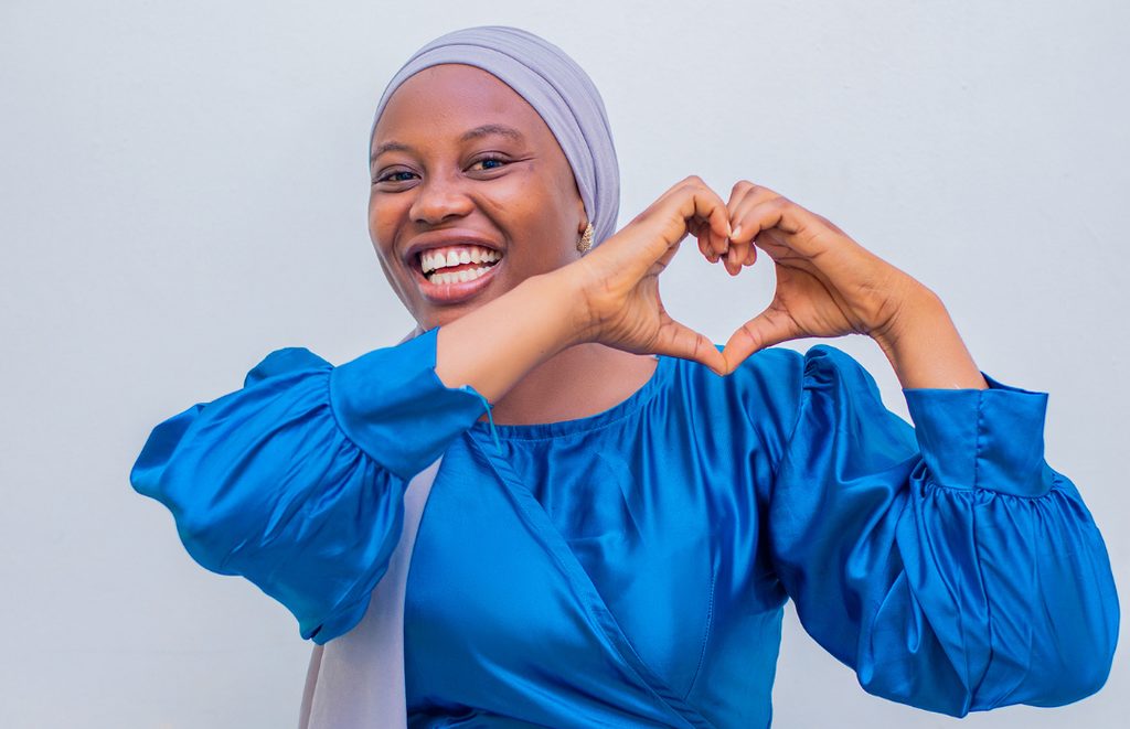 A young woman making a heart shape with her hands to show support for Unite for Peace